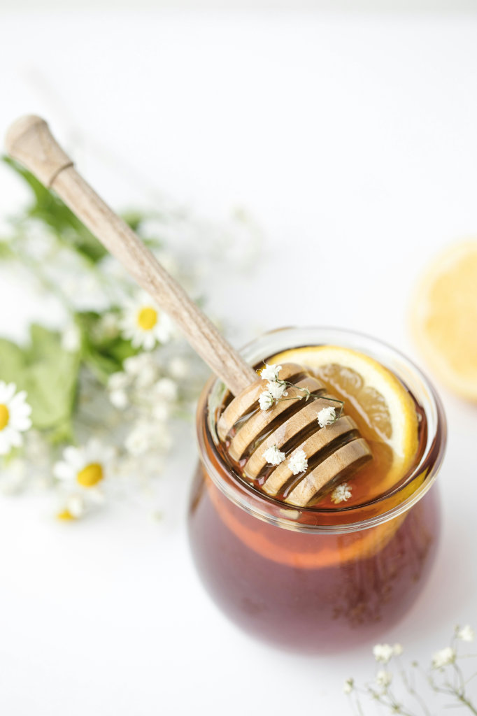 A honey dipper in honey with a slice of lemon.