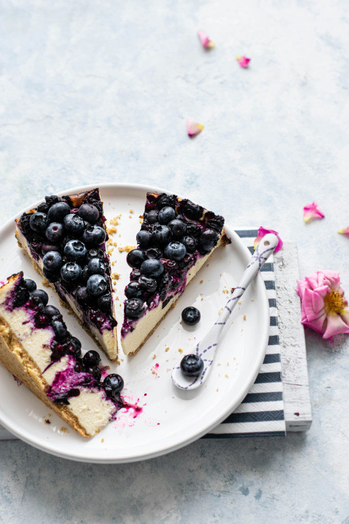 A platter of sliced blueberry cheesecake. 